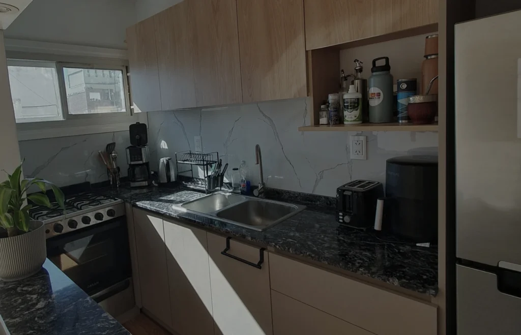 Cocina a medida en melamina símil roble con mesada de granito negro, proyecto Gascón en Mar del Plata