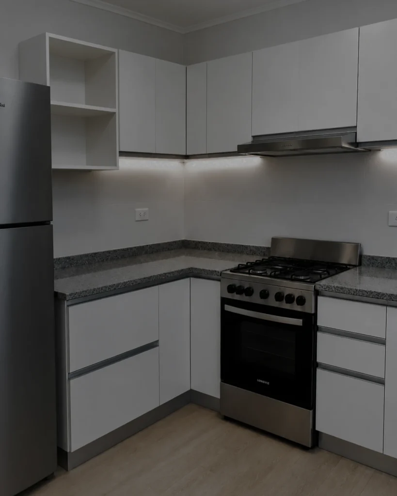 Cocina blanca a medida en L con mesada de granito gris, proyecto Matheu en Mar del Plata