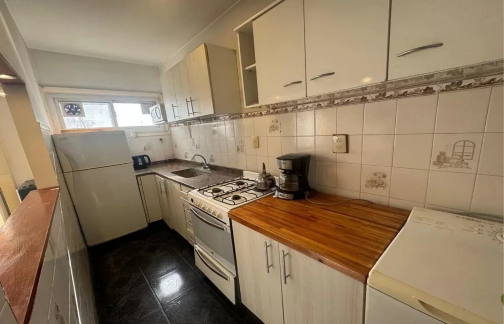 Cocina original antes de la reforma, con muebles blancos y mesada de madera