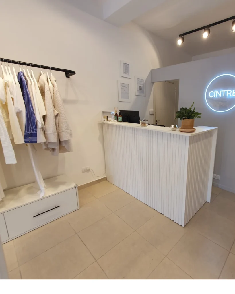 Salón del local con mostrador y perchero de pared con banco de guardado