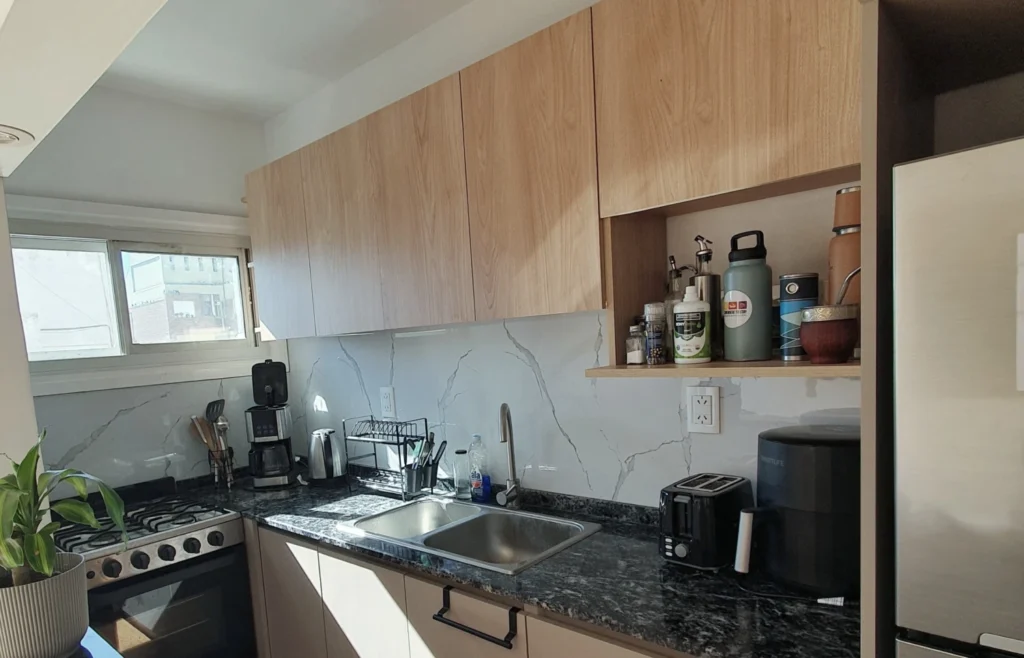 Vista general de la cocina Gascón con alacenas símil roble y frente símil mármol