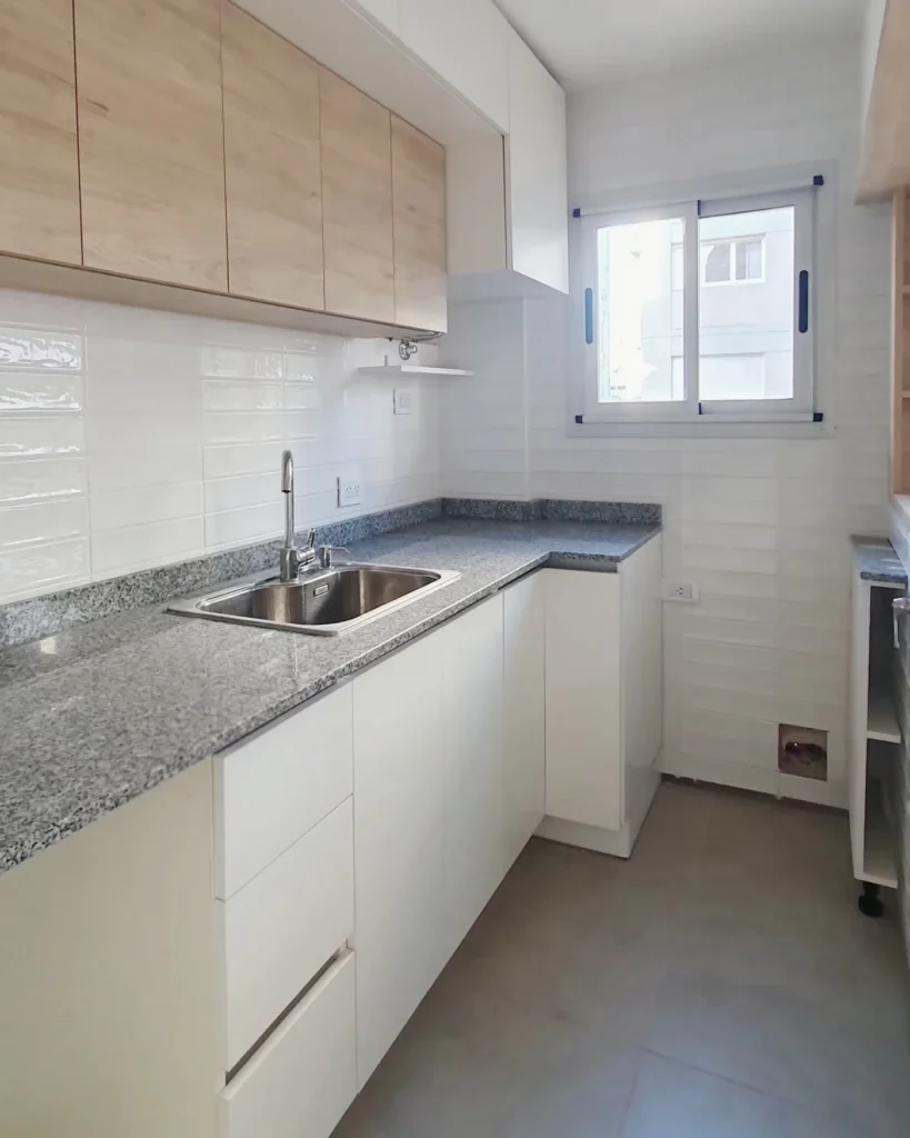 Cocina en L terminada, con alacenas símil roble y bajo mesada blancos