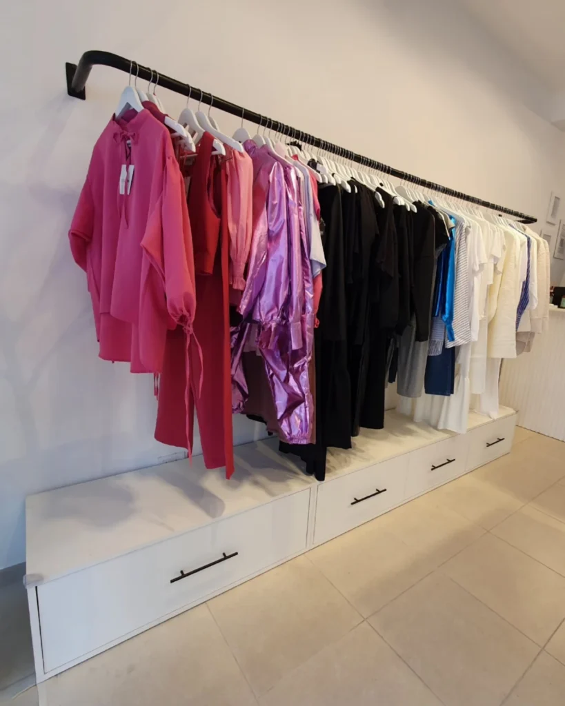 Perchero de pared con barral y banco bajo con cajones para exhibición