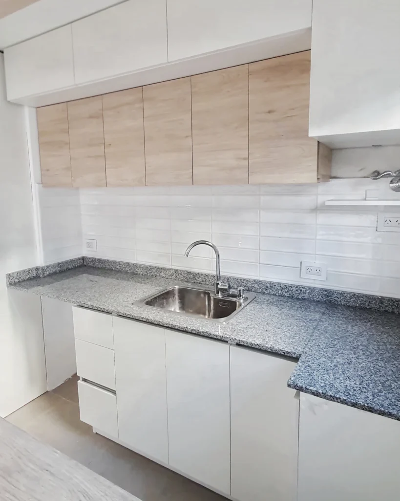 Mesada de granito gris con bacha simple y revestimiento subway blanco