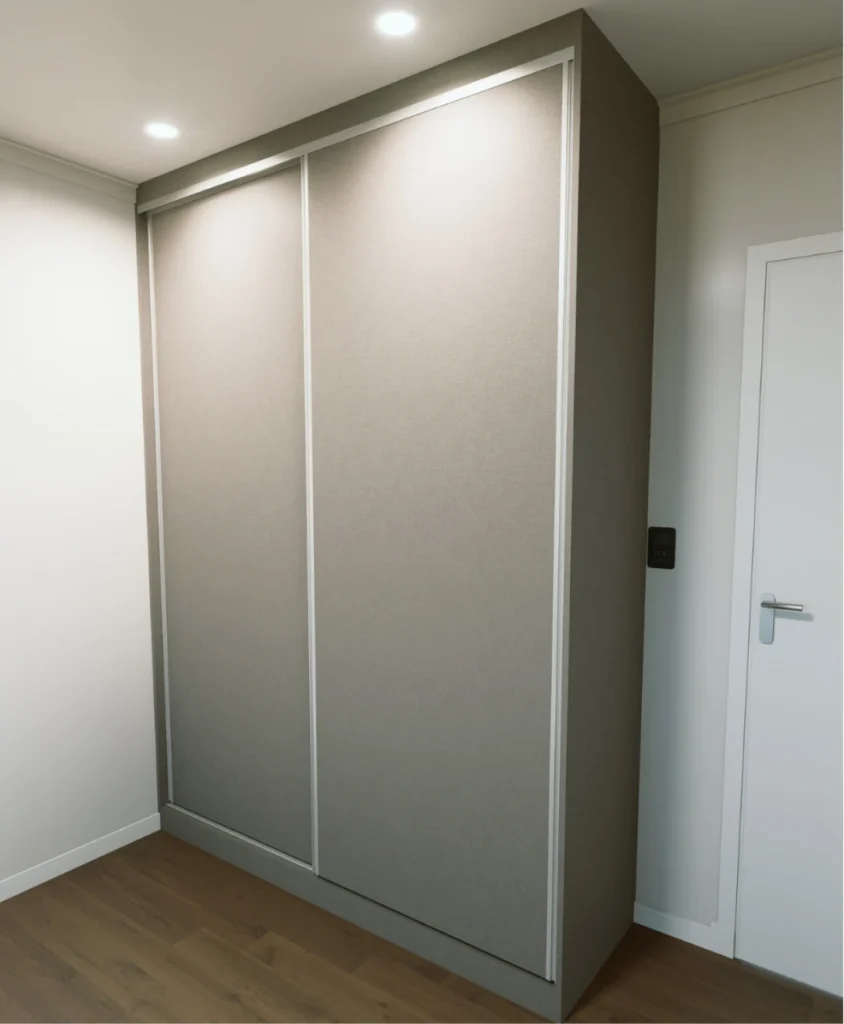 Placard cerrado con puertas corredizas color visón junto a la puerta del dormitorio