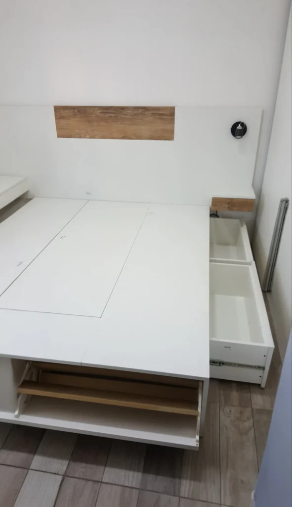 Cama box con cajón lateral abierto y espacio de guardado inferior